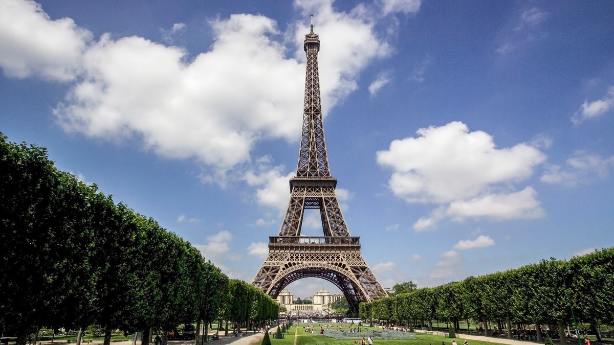 Un homme saute de la Tour Eiffel avec un parachute.  Il s’est caché dans les buissons pour échapper à la police