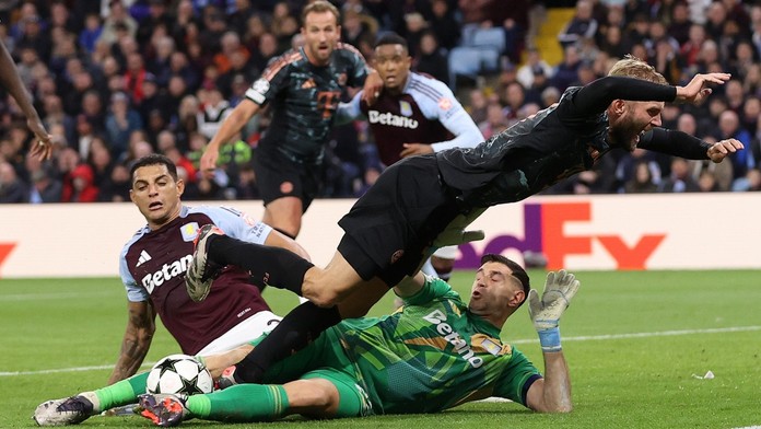 Emiliano Martínez (na zemi) zasahuje proti šanci Konrada Laimera z Bayernu