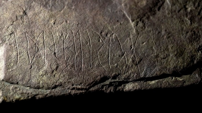 Archeology nadchl prastarý runový kámen. Nad nápisem si lámou hlavu
