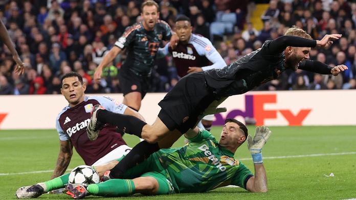 Emiliano Martínez (na zemi) zasahuje proti šanci Konrada Laimera z Bayernu
