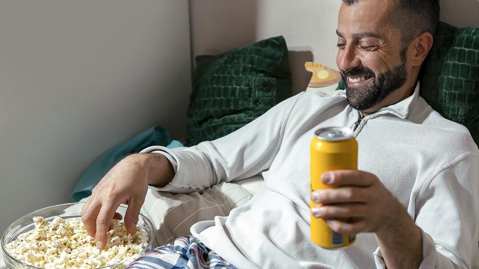 Muž s plechovkou a popcornem