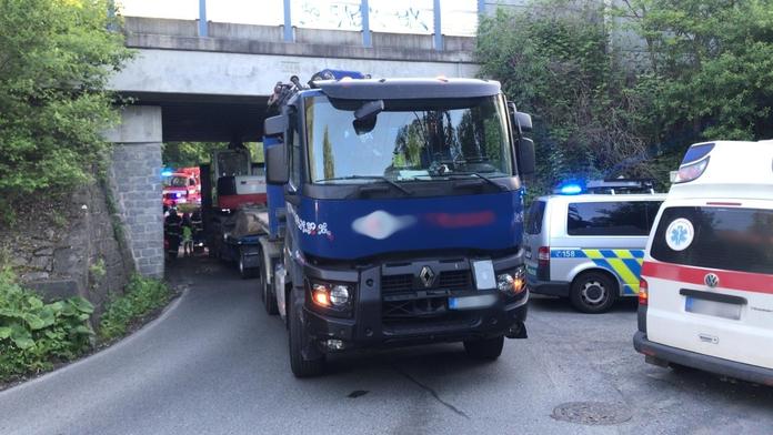 Řidič zapomněl na naložený bagr na korbě. Zasekl se pod mostem