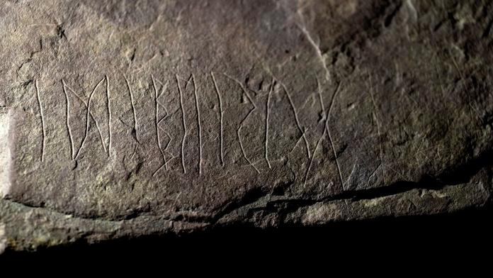 Archeology nadchl prastarý runový kámen. Nad nápisem si lámou hlavu