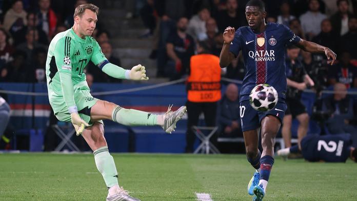 Brankář Bayernu Manuel Neuer vykopává míč před Ousmanem Dembélém z PSG