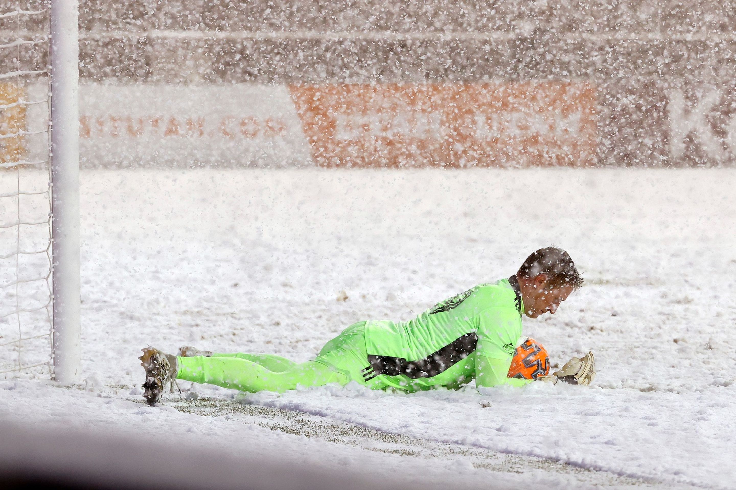Brankář Kansasu Tim Melia svírá ve svém náručí kromě míče i hroudu sněhu - GALERIE: Velká sněhová bitva! Hřiště v Salt Lake City zasypala vánice (10/13)